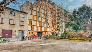 A multi-story residential building with a parking area in front. - La Suite Yak - Très beau studio - Charpennes-Tonkin (Villeurbanne)
