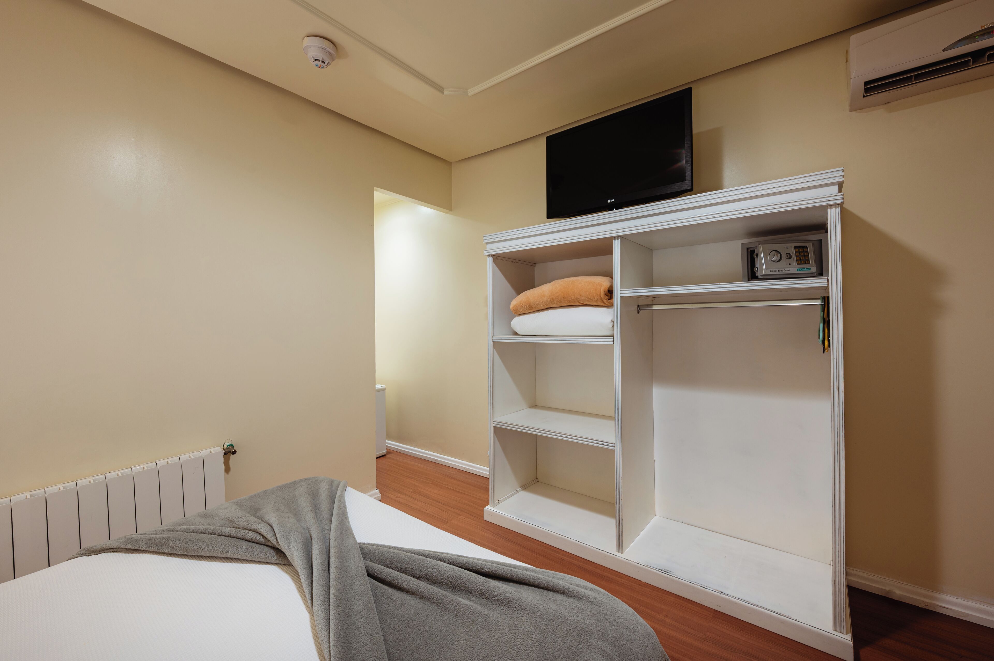 Une chambre à coucher avec un lit, une armoire, un téléviseur et un radiateur.