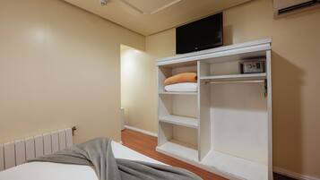 Une chambre à coucher avec un lit, une armoire, un téléviseur et un radiateur.