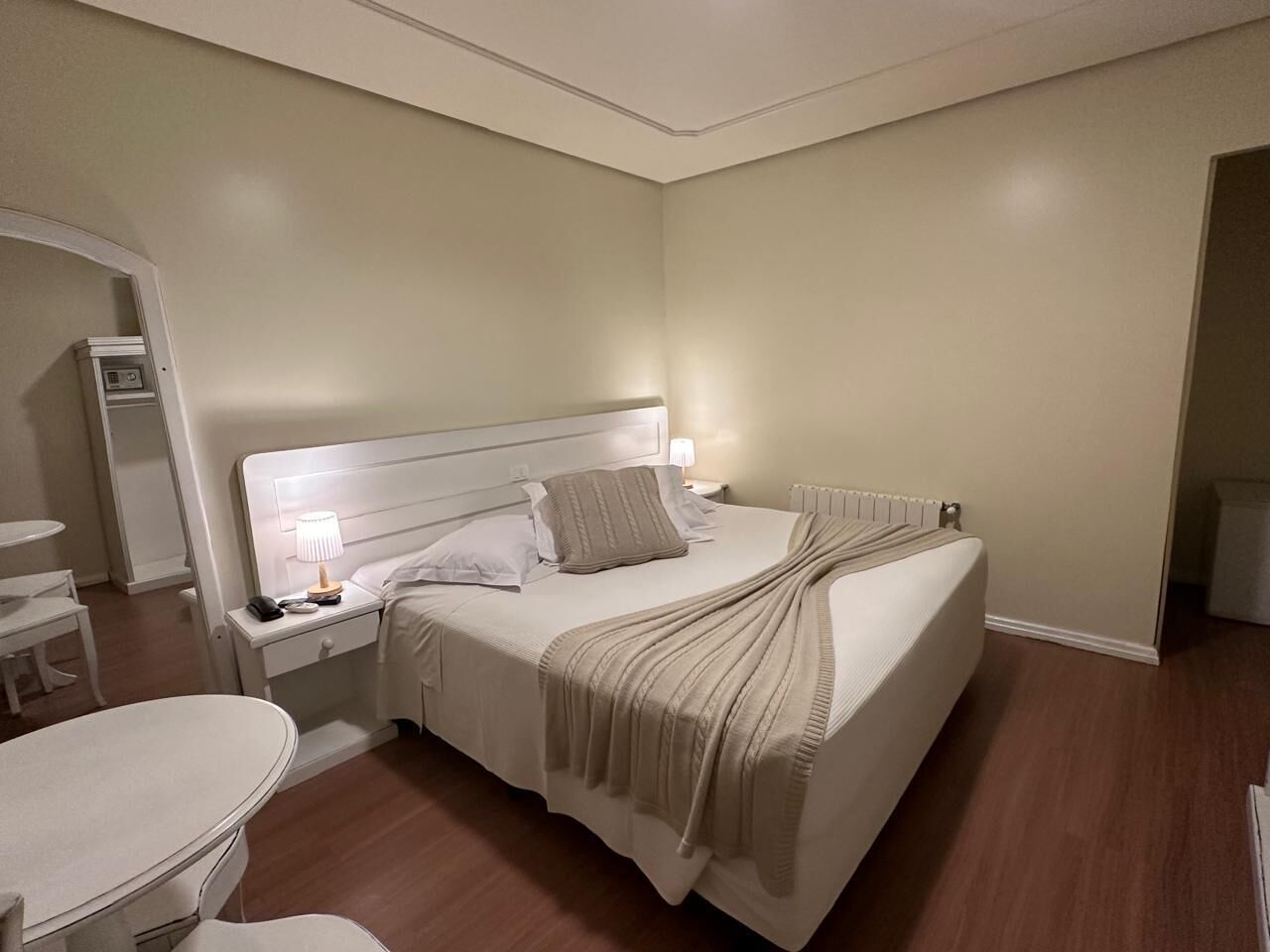 A neatly arranged bedroom with a bed, bedside tables, a chair, and a small table.