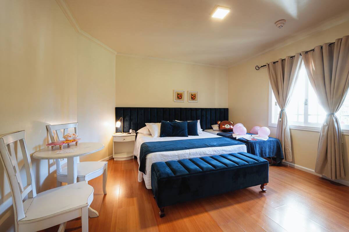 A neatly arranged bedroom with a bed, bedside tables, a chair, and a small table.