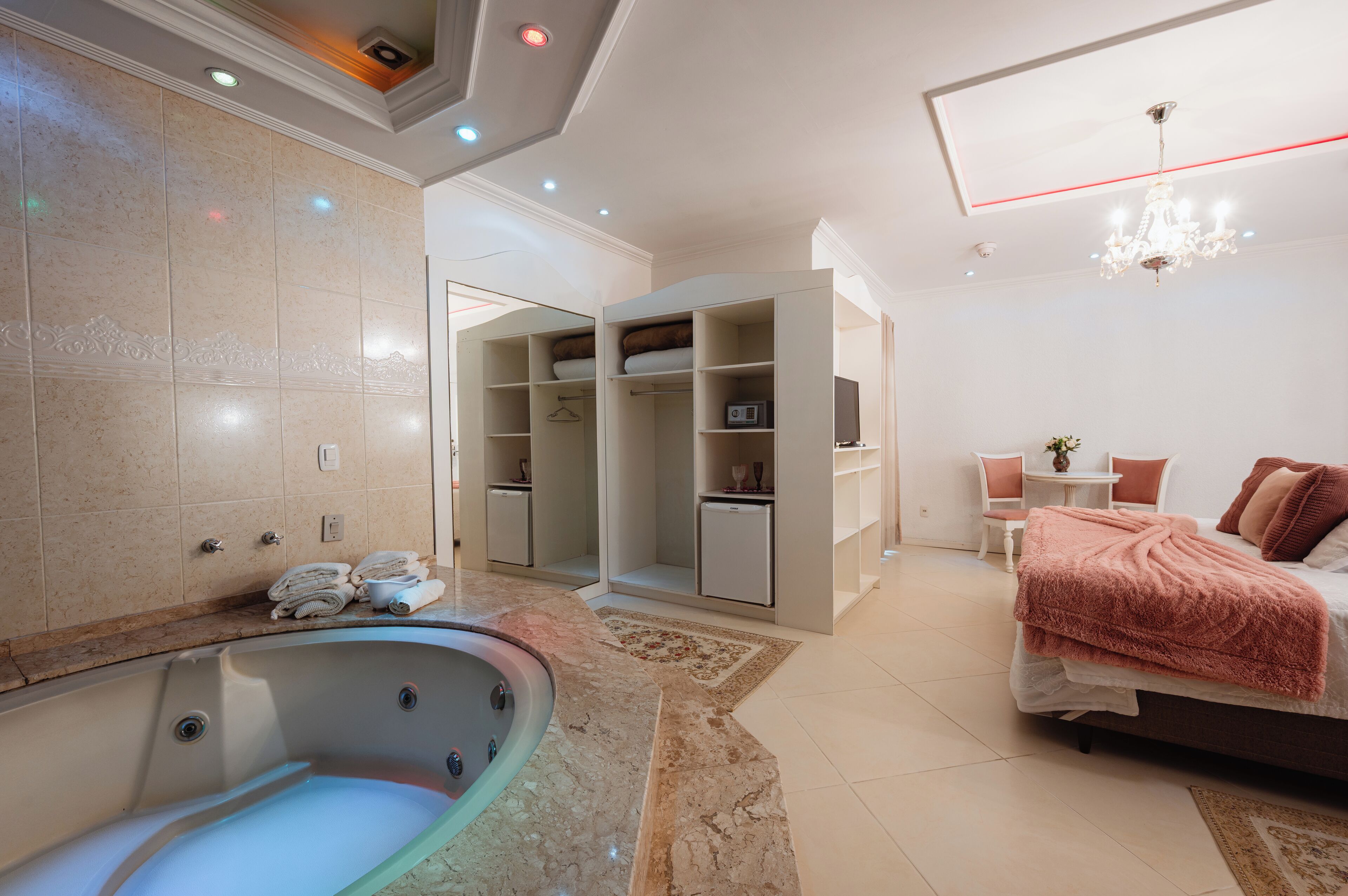 Une salle de bain moderne avec une baignoire, un dressing et une chambre à coucher avec un lit et un lustre.