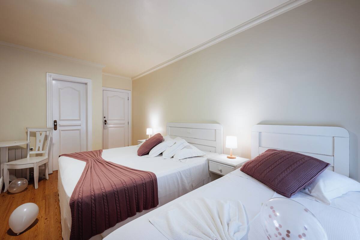 A hotel room with two beds, a desk, and a chair.