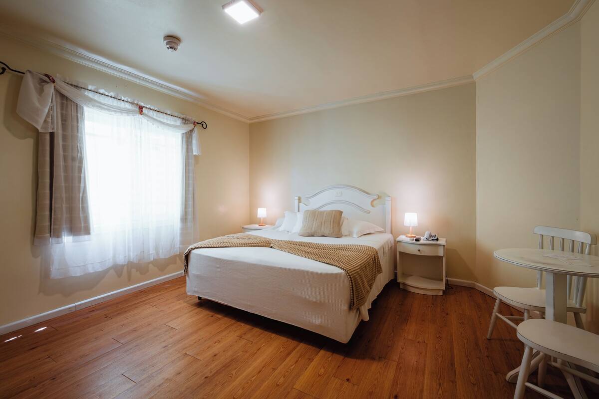 A bedroom with a bed, bedside tables, a chair, and a window with curtains.
