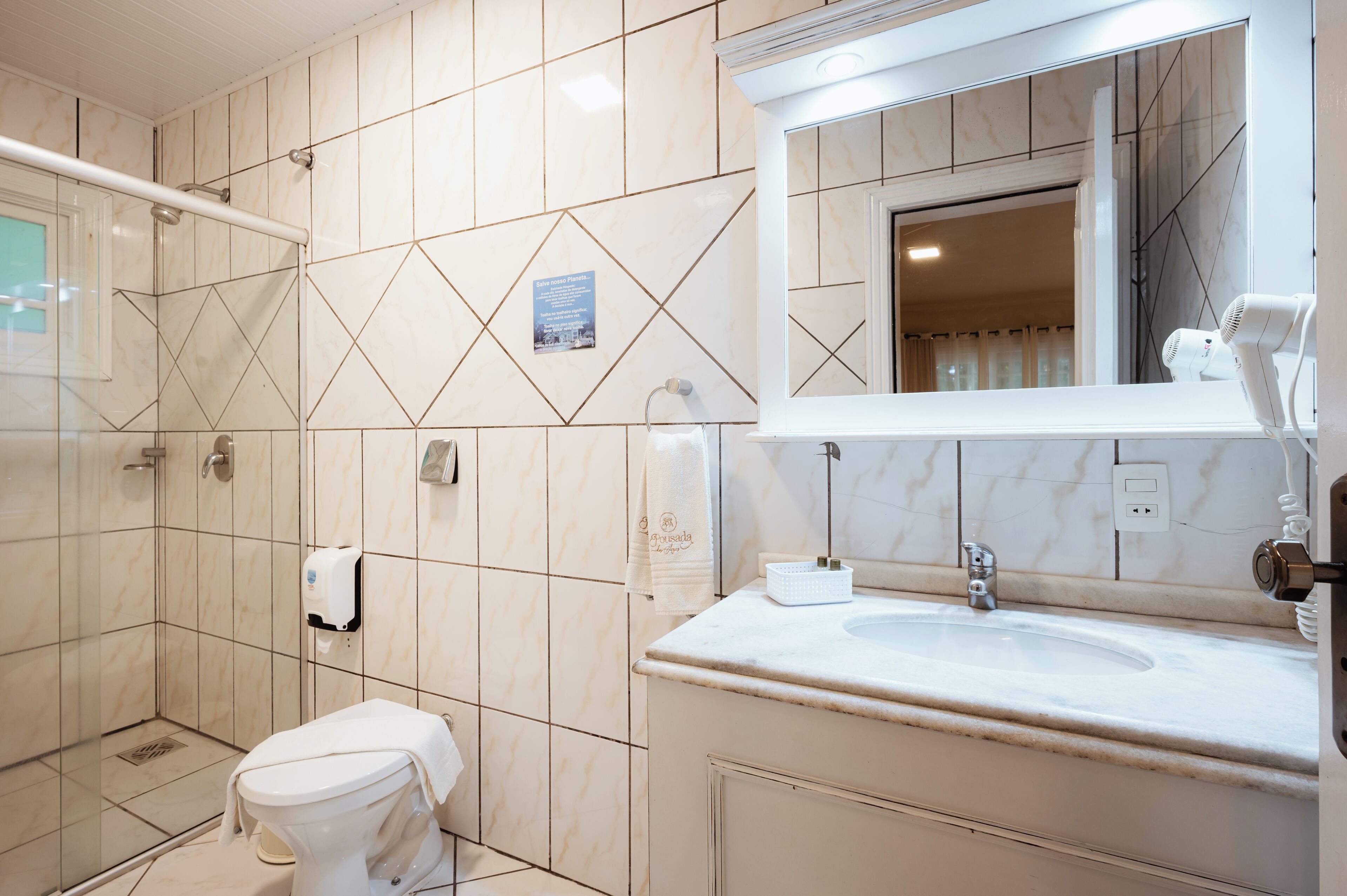 A bathroom with a shower, toilet, sink, and mirror.