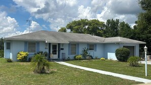 A single-story house with a front porch, a small front yard, and a clear sky. - Charming 3-bedroom house with lake views in serene Spring Hill (Spring Hill)