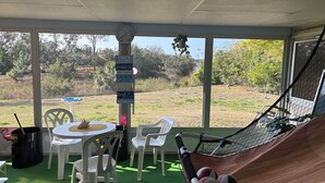 A covered outdoor seating area with a hammock, chairs, and a table. - Charming 3-bedroom house with lake views in serene Spring Hill (Spring Hill)