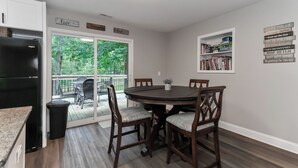A dining area with a round table and four chairs, a black refrigerator, and a bookshelf with various items. -  Lake Tillery Area, 4-bedroom house in charming Norwood with WiFi, Deck and AC (Norwood)