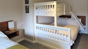 Een slaapkamer met een stapelbed, nachtkastje en een klein tafeltje.