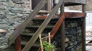 Een gebouw van steen met een houten trap naar een deur.