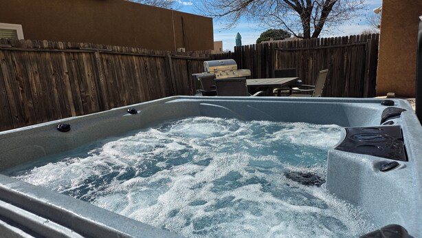A hot tub with a wooden fence and patio furniture in the background. - 50% Off Intro Rate @  Riverstone Retreat /4beds, 5G Fiber WiFi (Albuquerque)