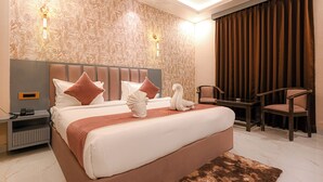 Habitació d'hotel moderna amb un llit gran, una tauleta de nit, una cadira i una làmpada penjada a la paret.