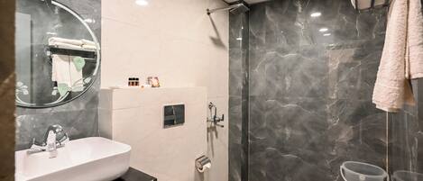 Un baño moderno con un lavamanos blanco, inodoro y ducha con mampara de vidrio.