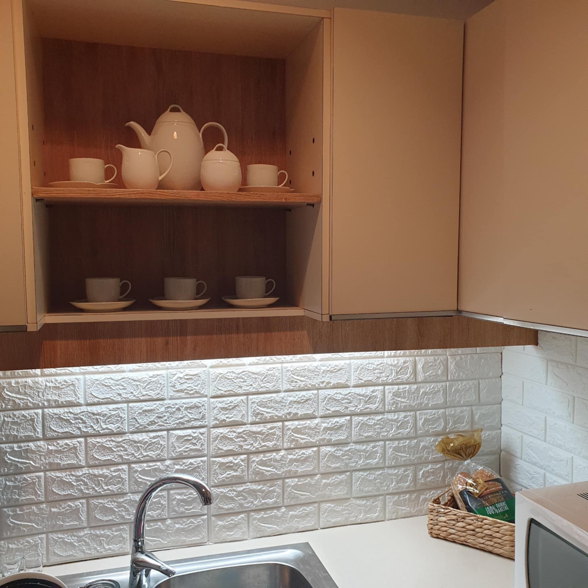 Eine Küche mit Holzausstattung, einer weißen Fliesenküchenwand und einer Edelstahlspüle.