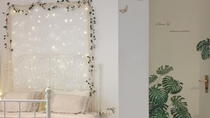 Un dormitorio con cama, cabecera de metal blanco y pared decorada con un mural de jardín botánico.