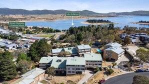 An aerial view of a residential area with multiple buildings, a school, and a lake. - Kirwan 8, 2 bedroom apartment (Jindabyne)