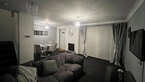 Una sala de estar con un sofá, un televisor y un comedor con sillas y una mesa.