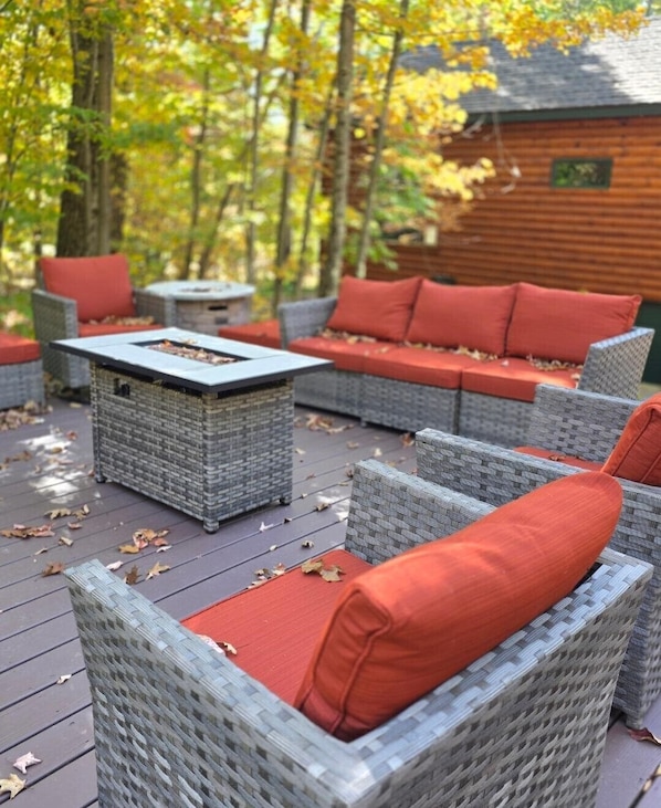 An outdoor wicker furniture set with red cushions on a wooden deck.