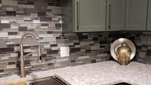 A kitchen with dark green cabinets, a tiled backsplash, a stainless steel sink, and a decorative Buddha head. - 1 Mile From Ski Slope and Festivals - 125 Nightly Fee (Hunter)