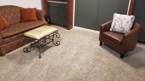 A living room with a patterned sofa, a bench, a brown leather armchair, and a cabinet. - 1 Mile From Ski Slope and Festivals - 125 Nightly Fee (Hunter)