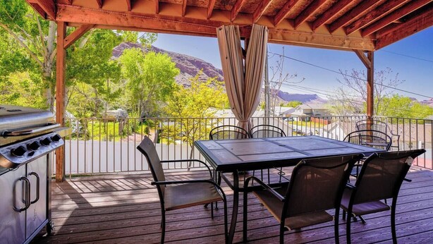 Une terrasse extérieure équipée d’un barbecue, d’une table et de chaises, offrant une vue sur un paysage montagneux.