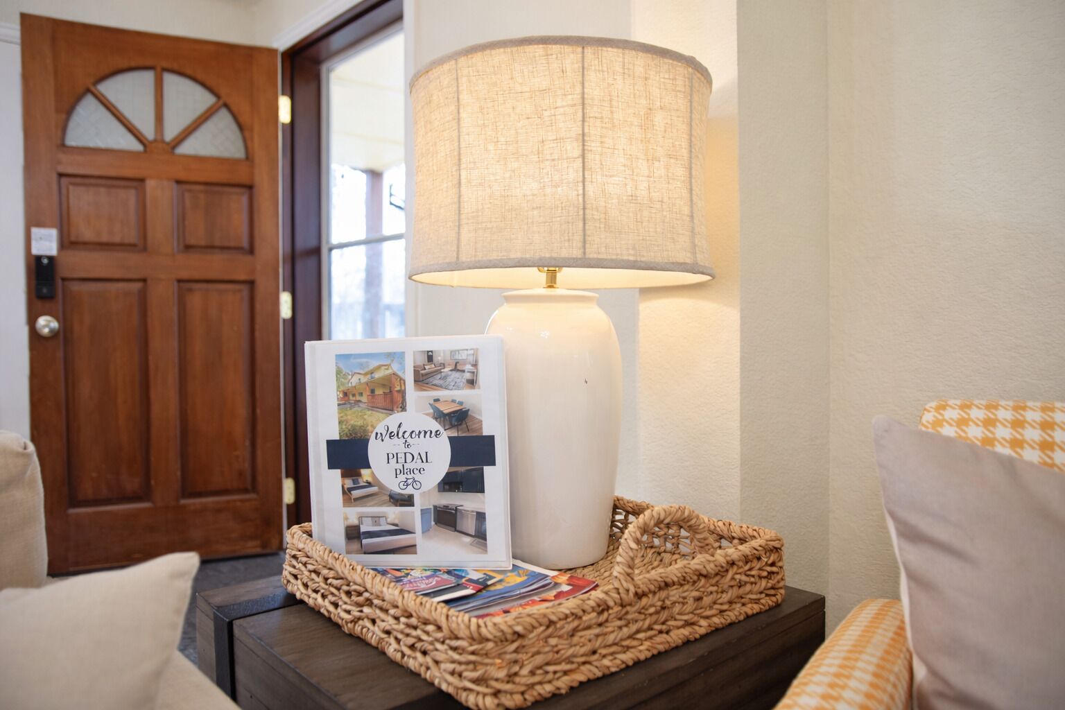 A lamp, a welcome sign, and a wicker basket on a bedside table.