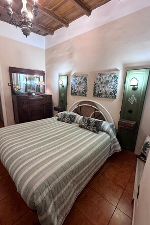 A bedroom with a bed, dresser, mirror, wall art, and a green door. - Antica Residenza del Corso Viterbo apartment Guglielmo Marconi. (Viterbo)