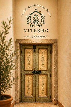 A door with a decorative design and the text 'Antica Residencia del Corso Viterbo - Boutique Residence' above it.