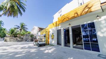 A building with a yellow and white facade, a parked golf cart, and palm trees in the background.