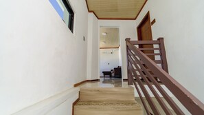 A staircase with wooden steps and a wooden handrail, leading to a room with a ceiling fan and a chair. - VelaaVani - Turtle Hive Dhiffushi (Dhiffushi)