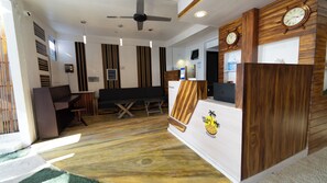 A reception area with a wooden reception desk, a clock, and a seating area with a sofa and a table. - VelaaVani - Turtle Hive Dhiffushi (Dhiffushi)