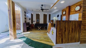 A reception area with a wooden desk, a clock, and a ceiling fan. - VelaaVani - Turtle Hive Dhiffushi (Dhiffushi)