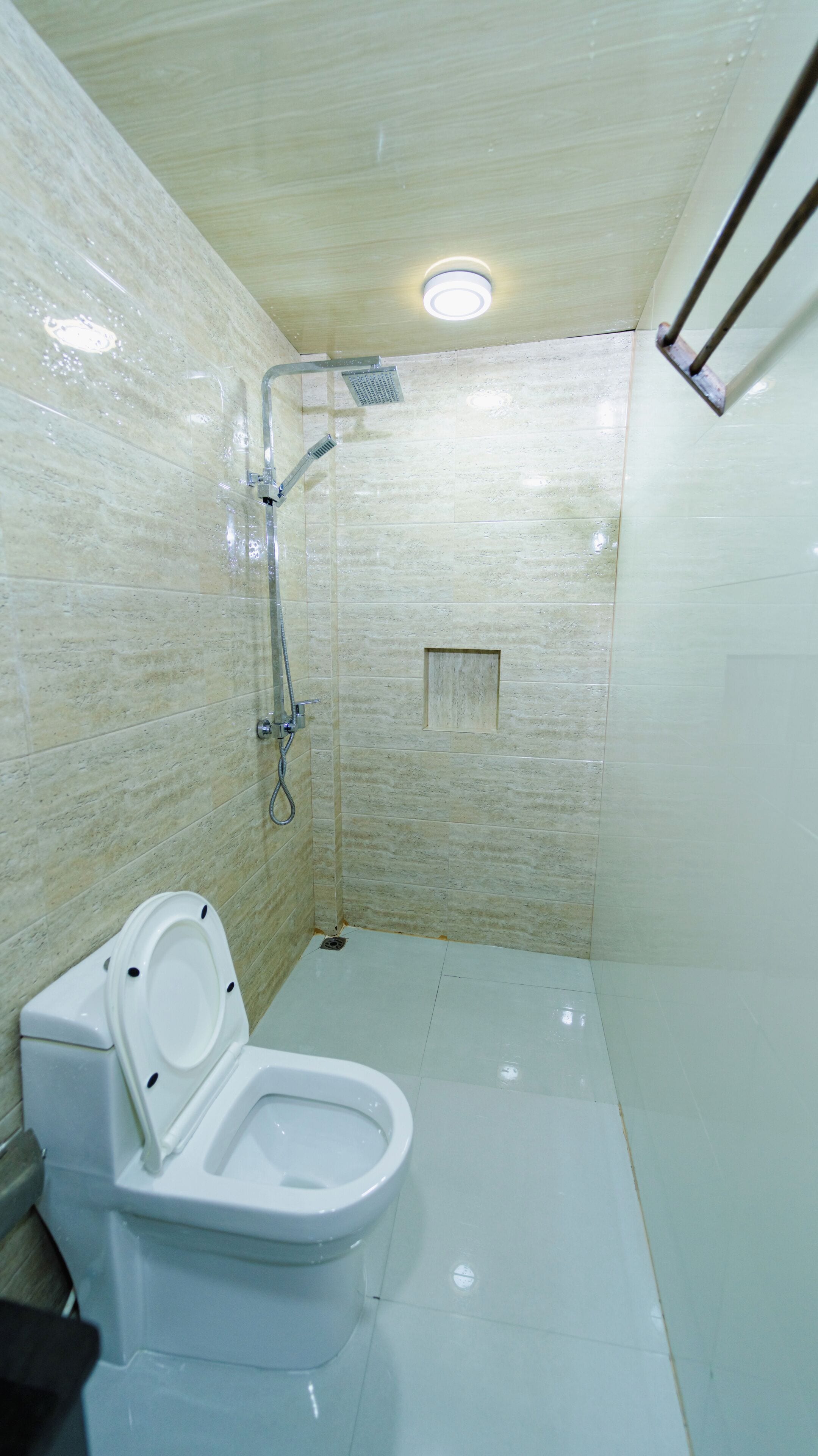 Un baño con inodoro, ducha y piso de baldosas.