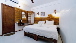 A bedroom with a wooden headboard, a bed with white bedding, a wooden wardrobe, a mirror, and a wall-mounted light fixture. - VelaaVani - Turtle Hive Dhiffushi (Dhiffushi)