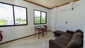 A room with a brown sofa, a small table with chairs, and two windows. - VelaaVani - Turtle Hive Dhiffushi (Dhiffushi)