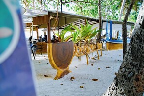 A wooden planter with a plant, a covered seating area, and a tree trunk. - VelaaVani - Turtle Hive Dhiffushi (Dhiffushi)