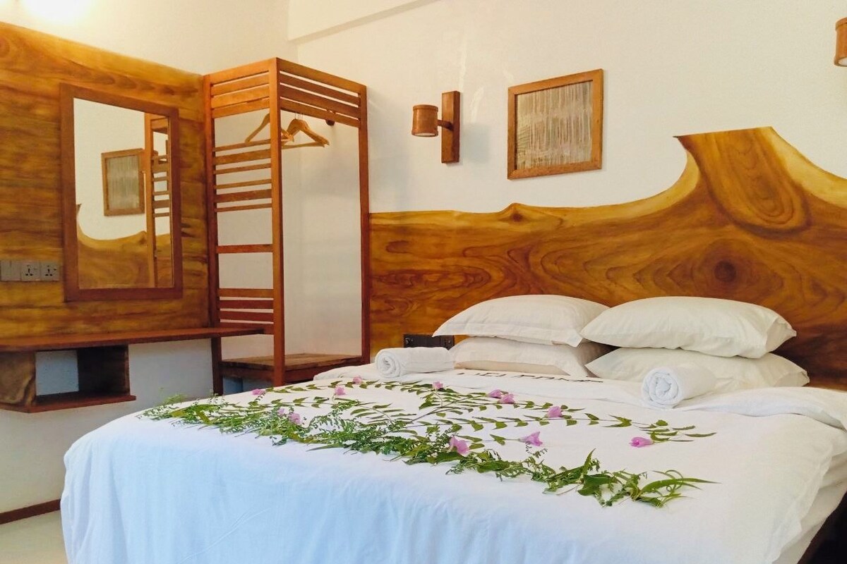 A bedroom with a wooden headboard, a bed with white linens, and a wooden ladder leaning against the wall.