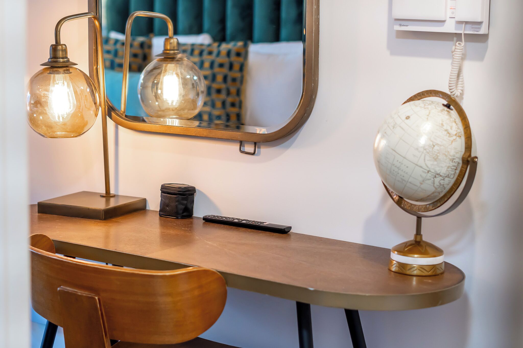 A wooden desk with a globe, a lamp, and a remote control.