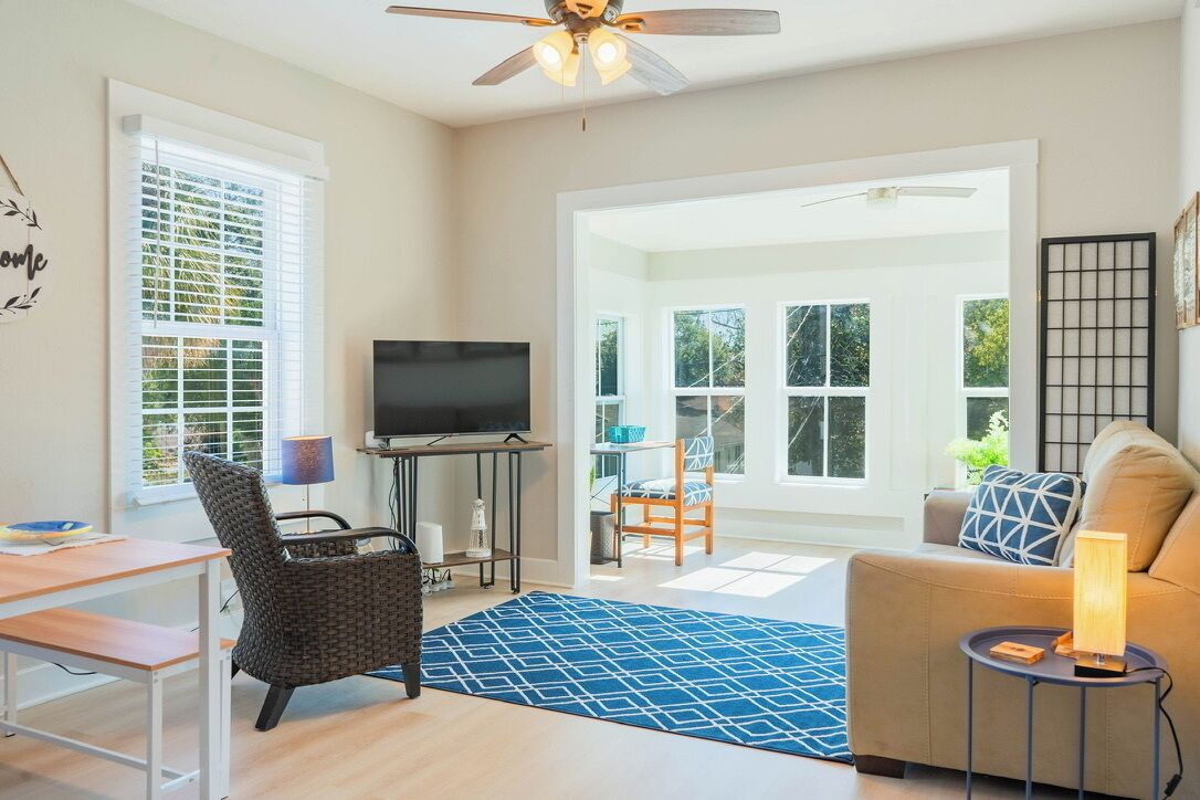 A living room with a TV, a sofa, a chair, a table, and a ceiling fan.