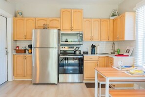 A compact kitchen with a refrigerator, oven, microwave, and wooden cabinets. - 1 BR Apt - Walk to Historic Hub (St. Augustine)