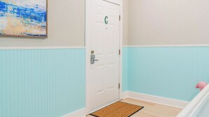 A room with a white door marked with a green 'C', a blue and white wainscoting, and a pink flamingo decoration. - 1 BR Apt - Walk to Historic Hub (St. Augustine)