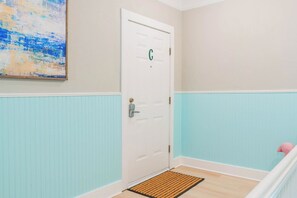 A room with a white door marked with a green 'C', a blue and white wainscoting, and a pink flamingo decoration. - 1 BR Apt - Walk to Historic Hub (St. Augustine)