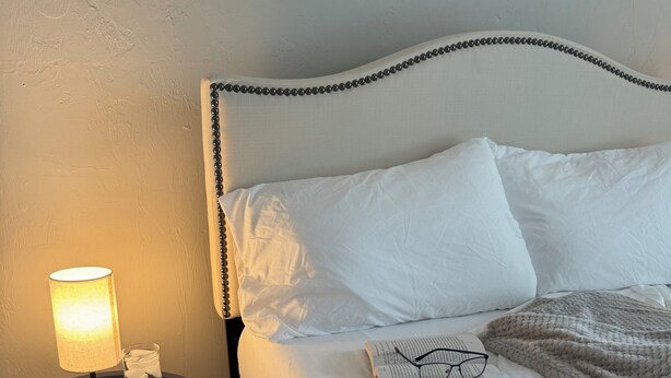 A neatly made bed with white bedding, a bedside lamp, and a book with glasses on it. - 1 BR Apt - Walk to Historic Hub (St. Augustine)