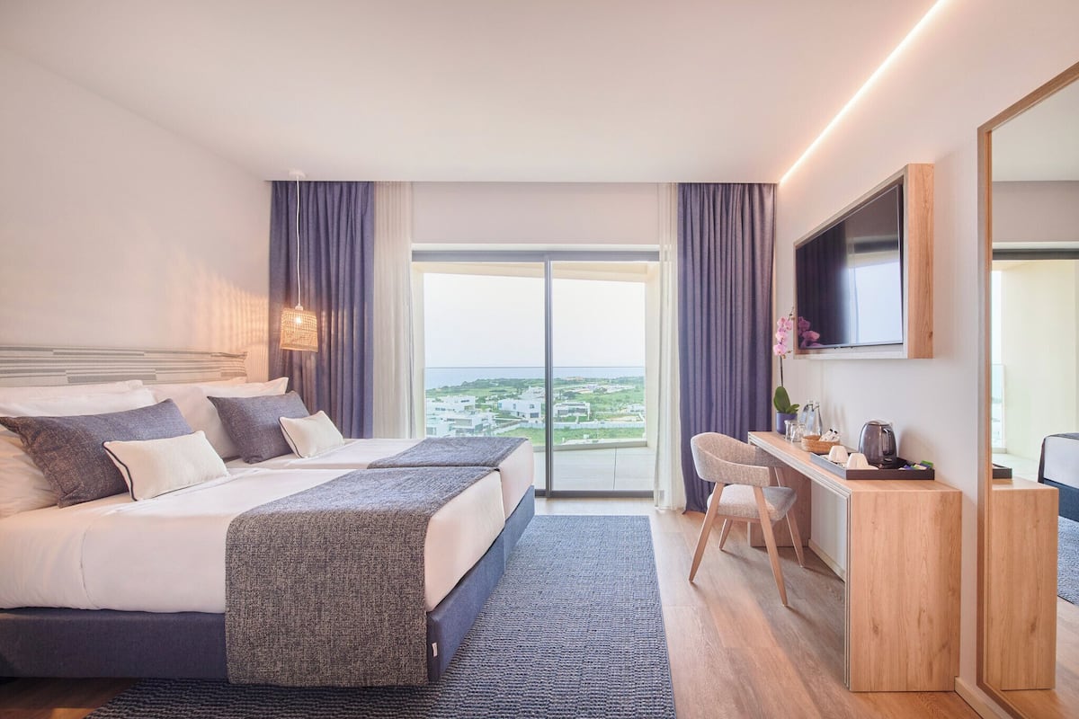 Ein modernes Hotelzimmer mit einem großen Bett, einem Schreibtisch und Blick auf die Stadt.