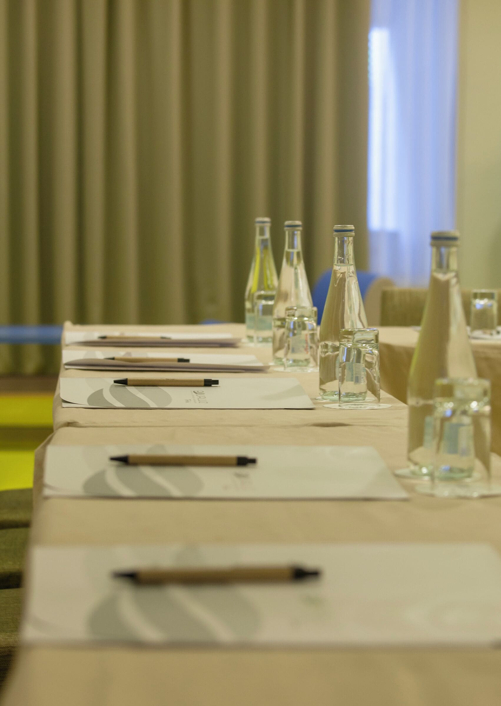 A conference table with documents, pens, and water bottles.
