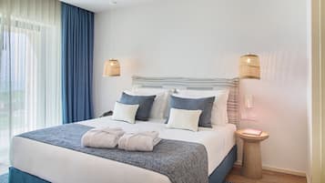 Une chambre d’hôtel avec un grand lit, deux lampes de chevet, une table de chevet et une vue dégagée à travers des rideaux légers.
