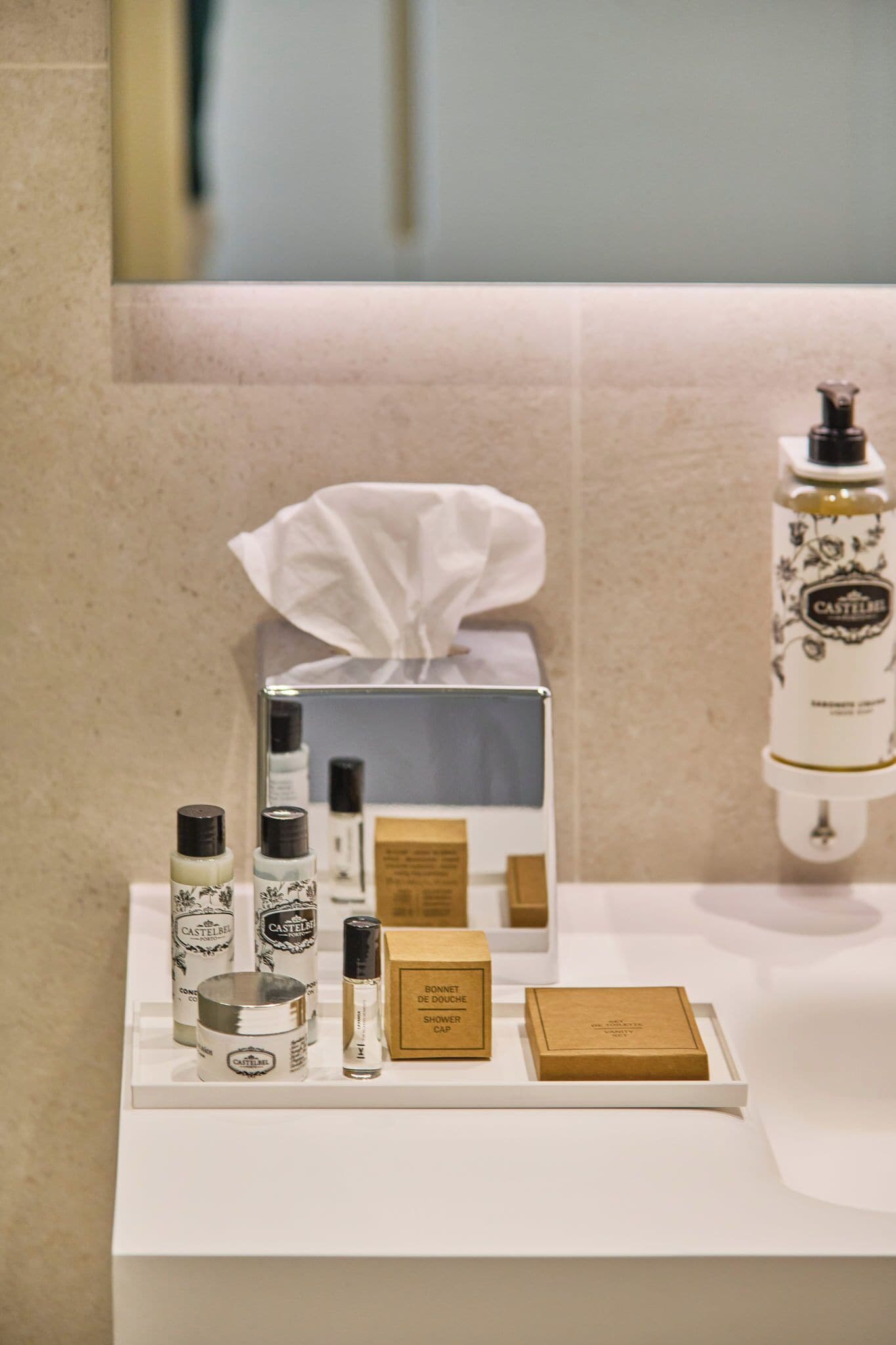 A bathroom vanity with toiletries including a bottle of Castille soap, a jar, and a box labeled "Bonde de Doux Showers".
