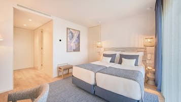 Une chambre d’hôtel moderne avec un grand lit, un petit coin salon et un tableau au mur.