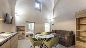 Een moderne keuken met een eethoek, een bank en een aan de muur bevestigde televisie.
