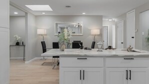 Cocina moderna con armarios blancos, encimera de mármol y una isla central con asientos.